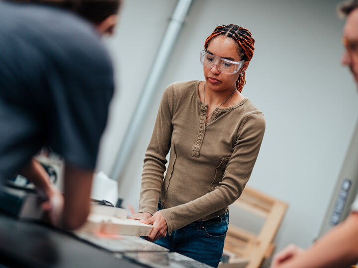 A student cutting lumber in the woodshop.